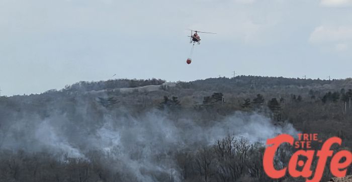 Duino Aurisina, incendio in corso: elicottero in azione tra fumo e vegetazione